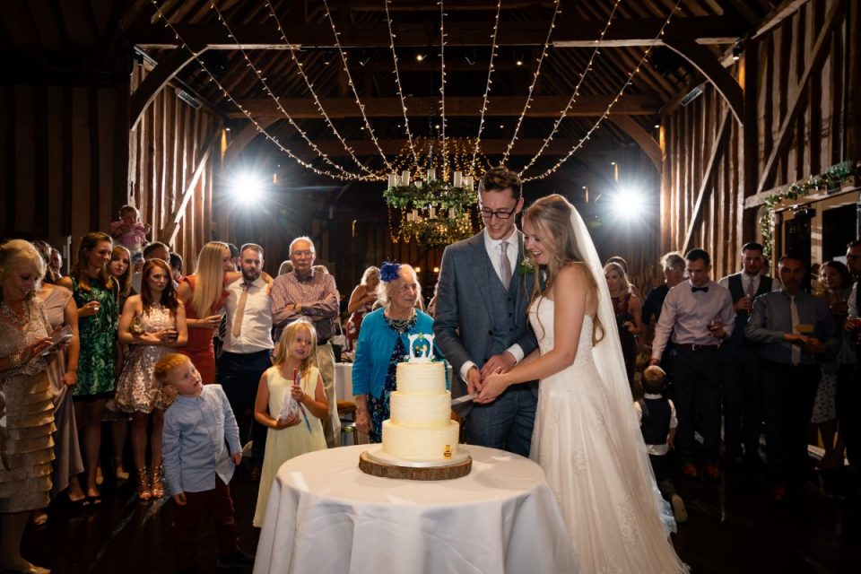 Jen and Joe cutting the cake at their barn wedding photographed by Andy Sidders.