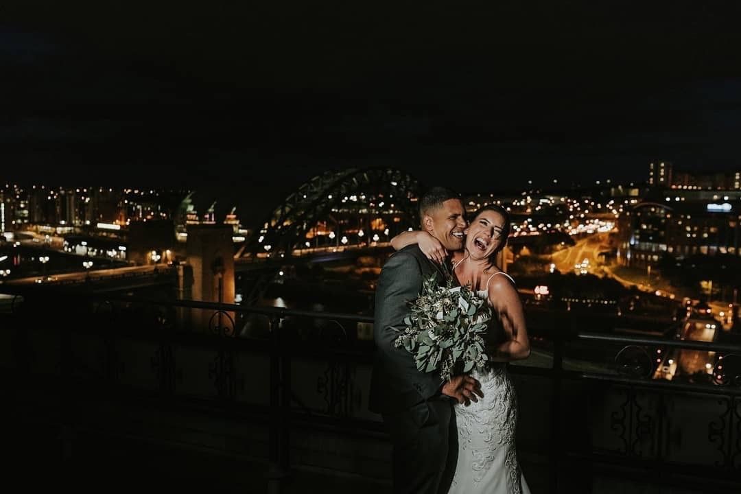 The happy couple in front of the beautiful city of Newcastle alight at night!